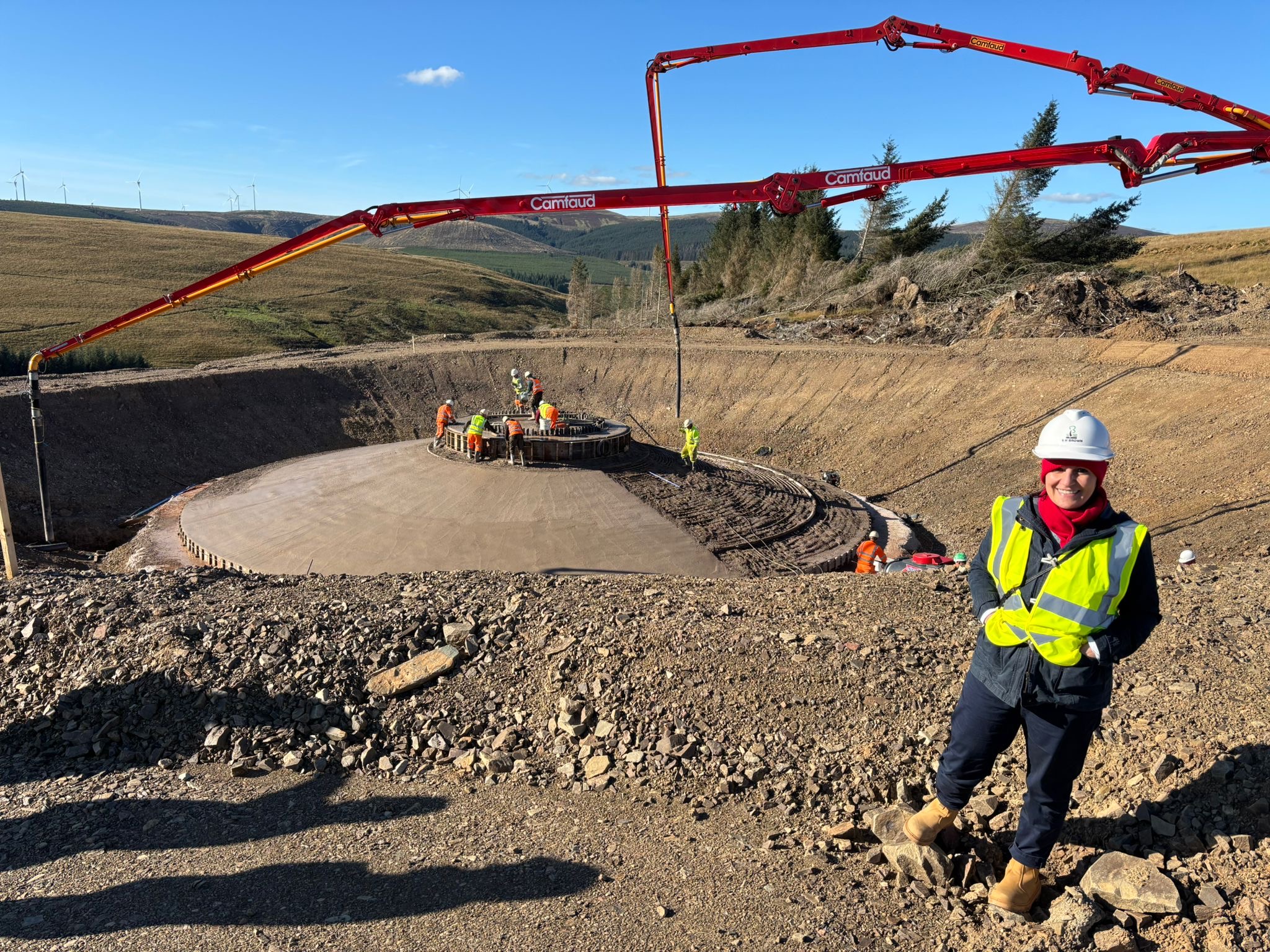 Person wearing high vis standing in front of construction site of a wind turbine